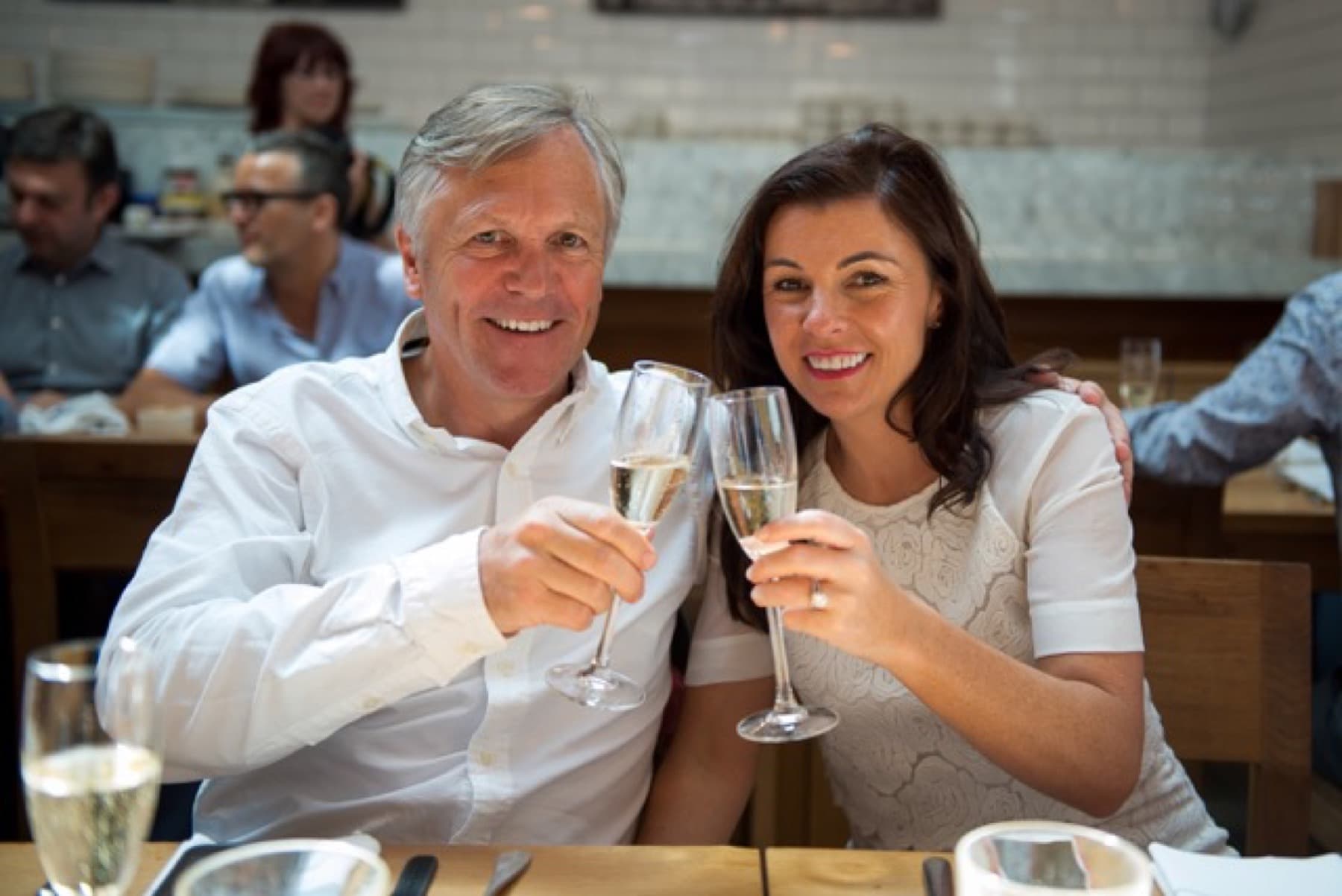 A smiling couple raising glasses together