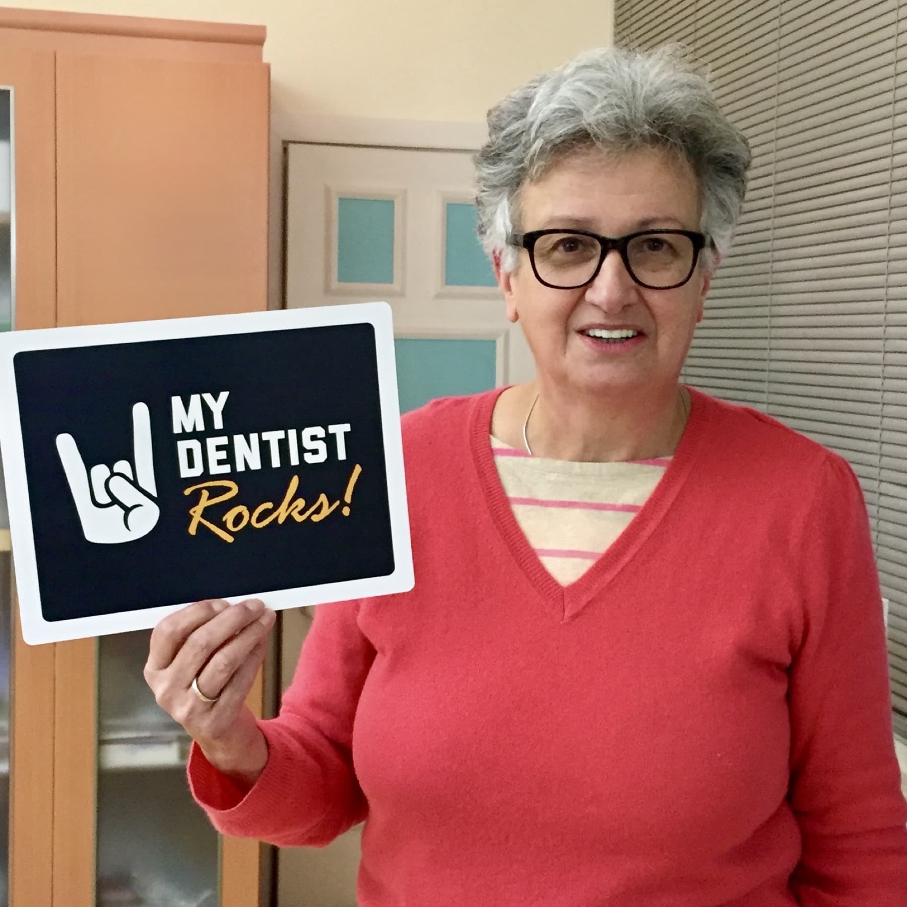 A happy patient holding a sign praising their dental treatment results